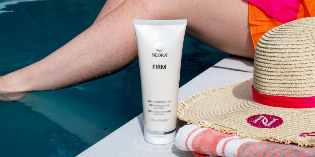 A bottle of Neora's Firm Contour Cream next to a woman poolside.