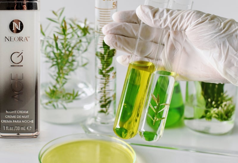 Image of Age IQ Night Cream bottle with a gloved hand holding test tubes In a lab setting