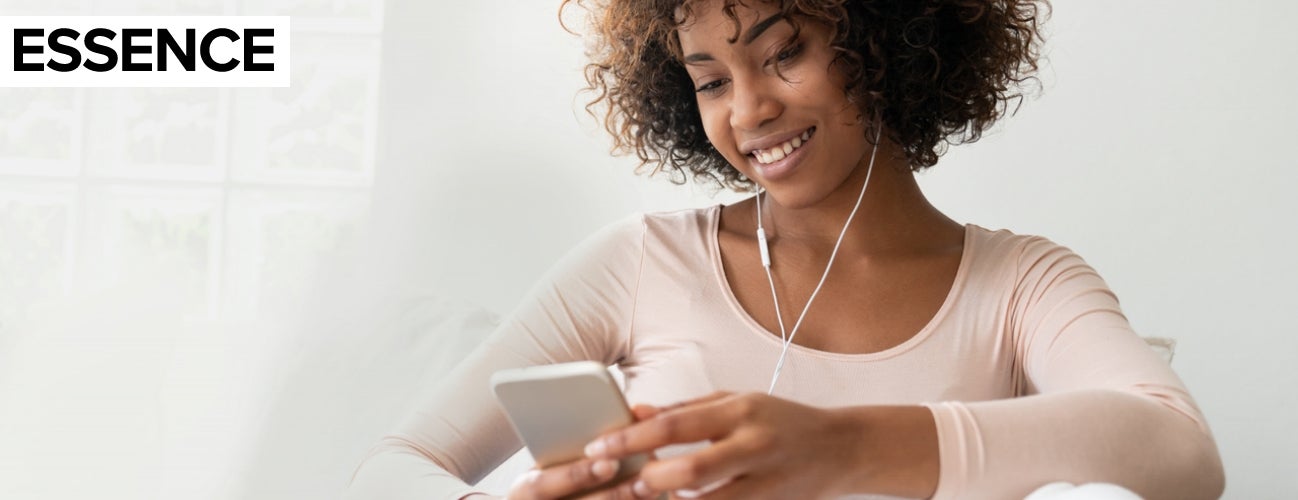 Image of a woman listening to music on headphones while using her cell phone.