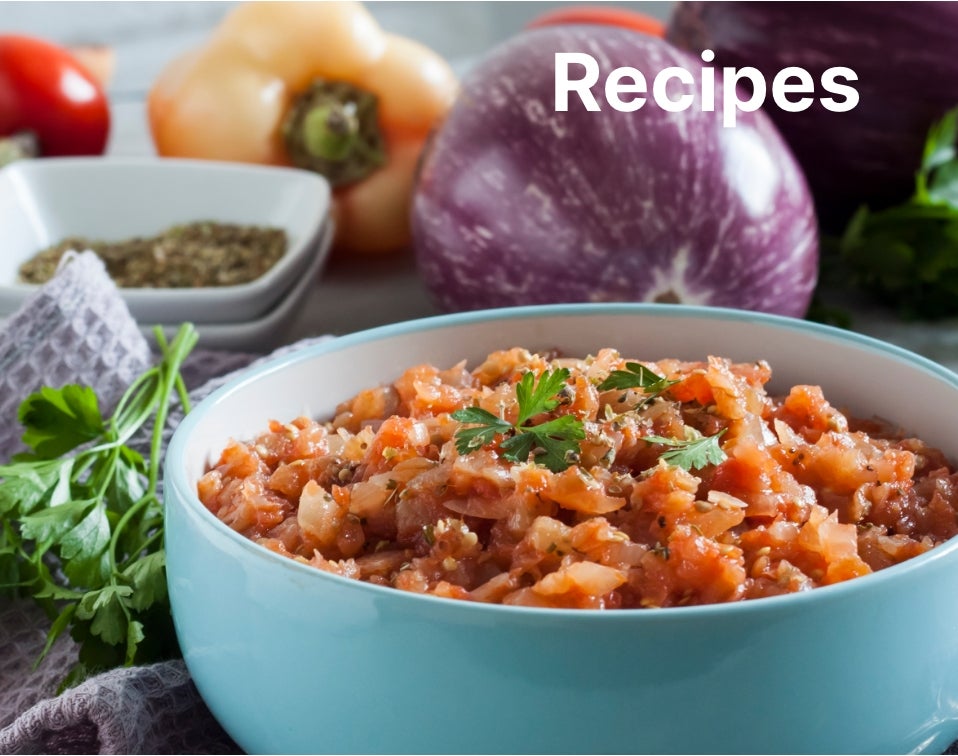 Recipes. A lifestyle shot of a salmon bowl with various vegetables behind it.