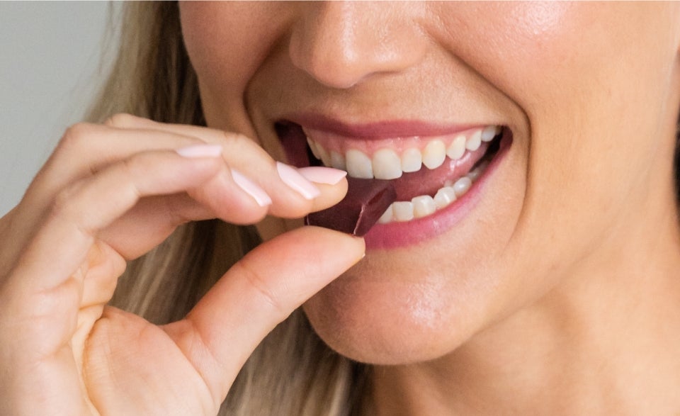 A woman biting into a Energy+ Wellness Chew.