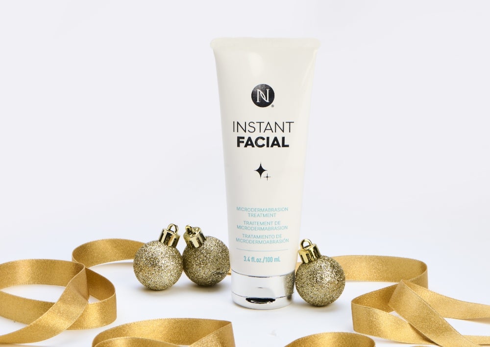 New limited-edition Instant Facial Microdermabrasion treatment. Achieve flawlessly smooth and clear skin for $97 retail or $80 with SmartShop. Background imagery includes a Neora Instant Facial tube surrounded by gold ribbon and ornaments.