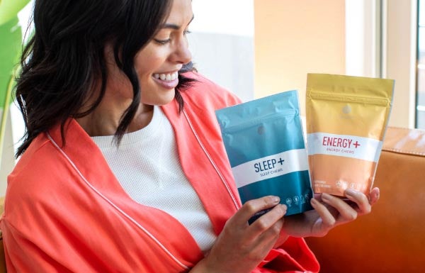 A woman holding up the Sleep+ Energy+ Wellness Chews Combo.