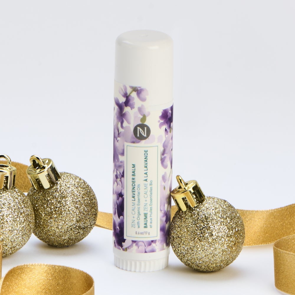 Neora’s Zen + Calm Lavender Balm container surrounded by gold ribbon and ornaments.