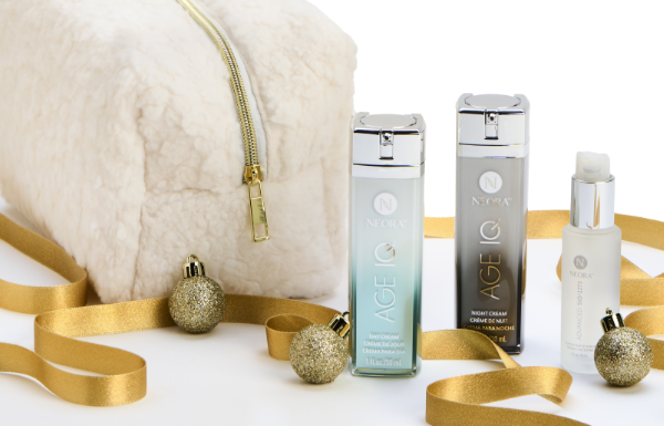 Neora’s Age IQ Day and Night Creams bottles & Sig Serum surrounded by gold ribbon and ornaments, and a white teddy plush bag.